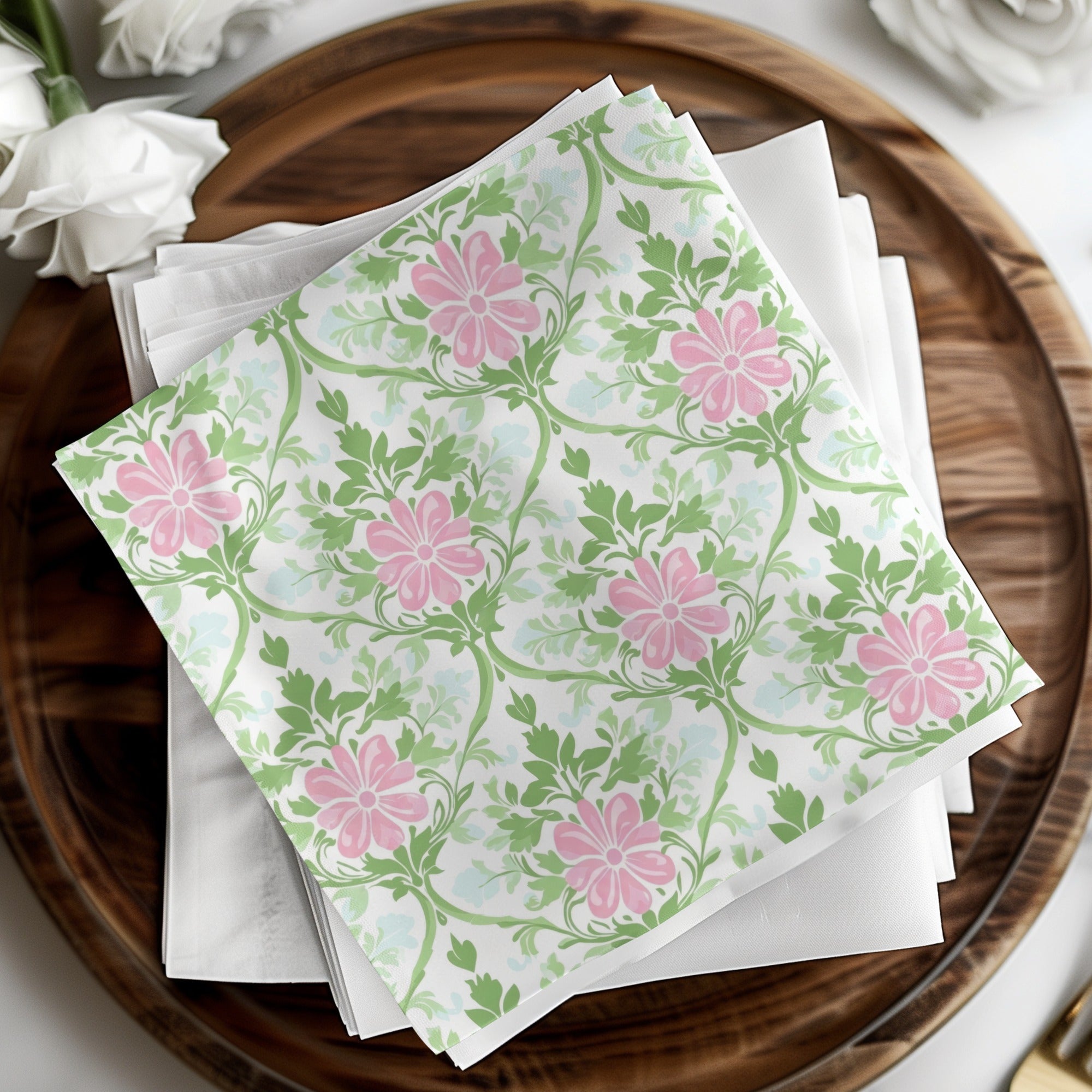 White cocktail napkins with a pink floral and green vine pattern.
