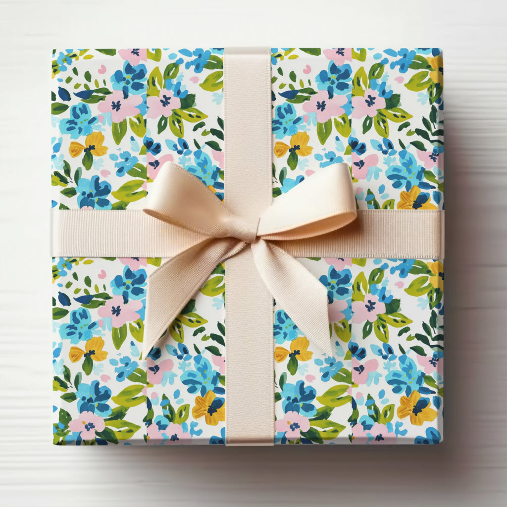 Gift-wrapped box with blue, pink, and yellow floral pattern and beige ribbon.