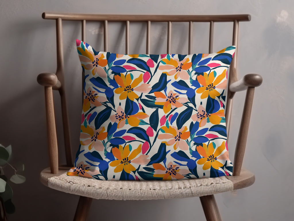 Decorative throw pillow with a vibrant floral pattern in orange, blue, and pink on a cream background.