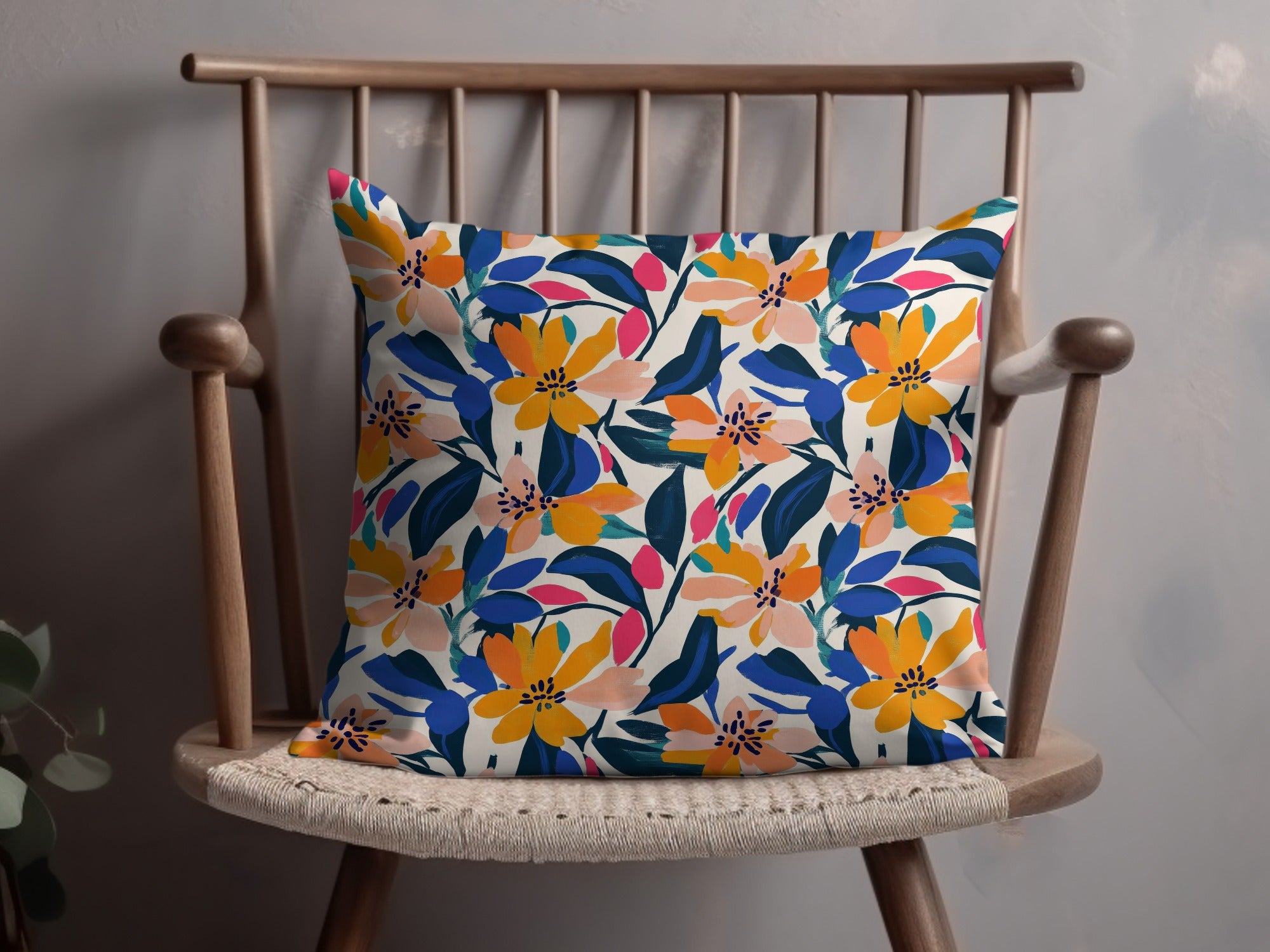 Decorative throw pillow with a vibrant floral pattern in orange, blue, and pink on a cream background.