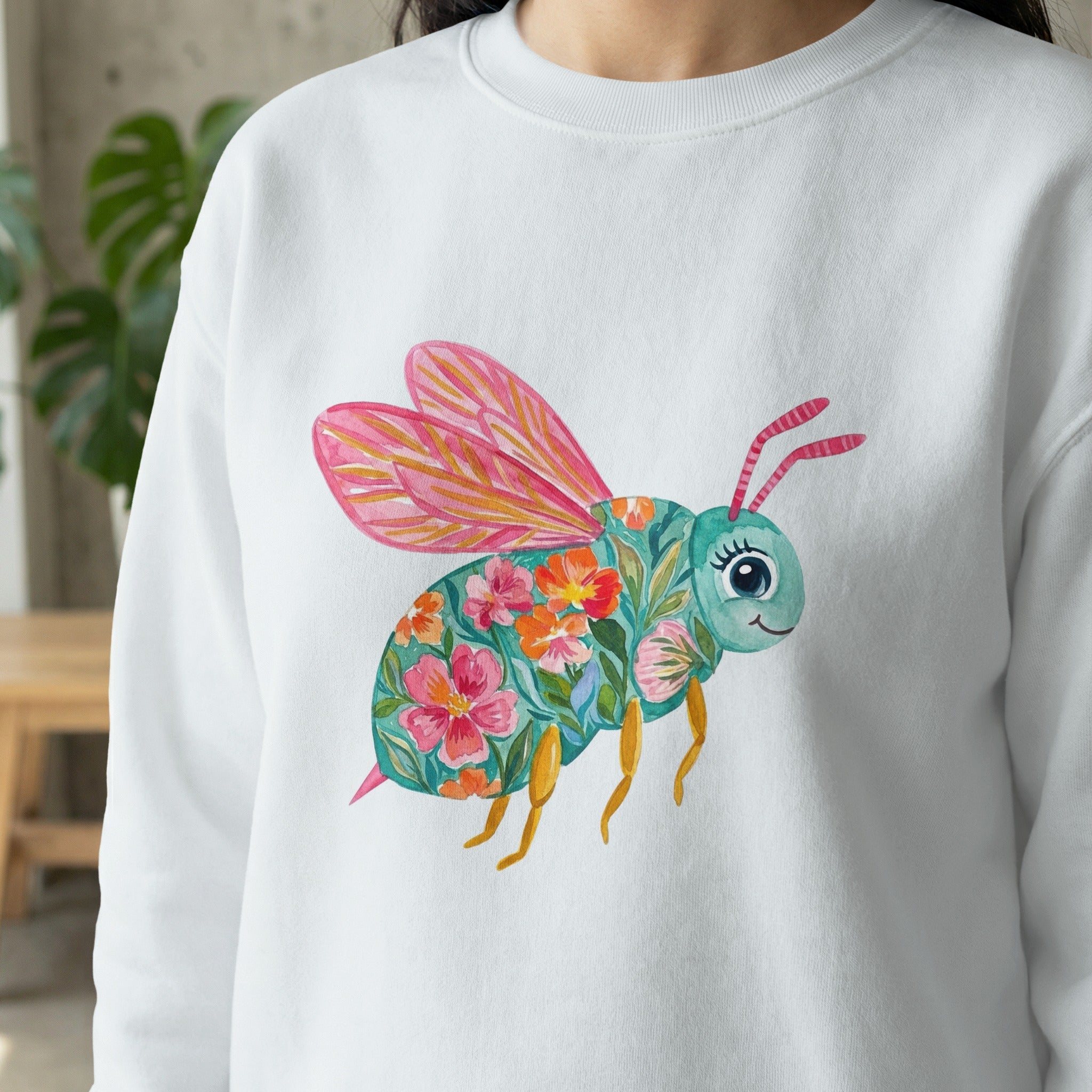 White sweatshirt with a colorful floral bee illustration.