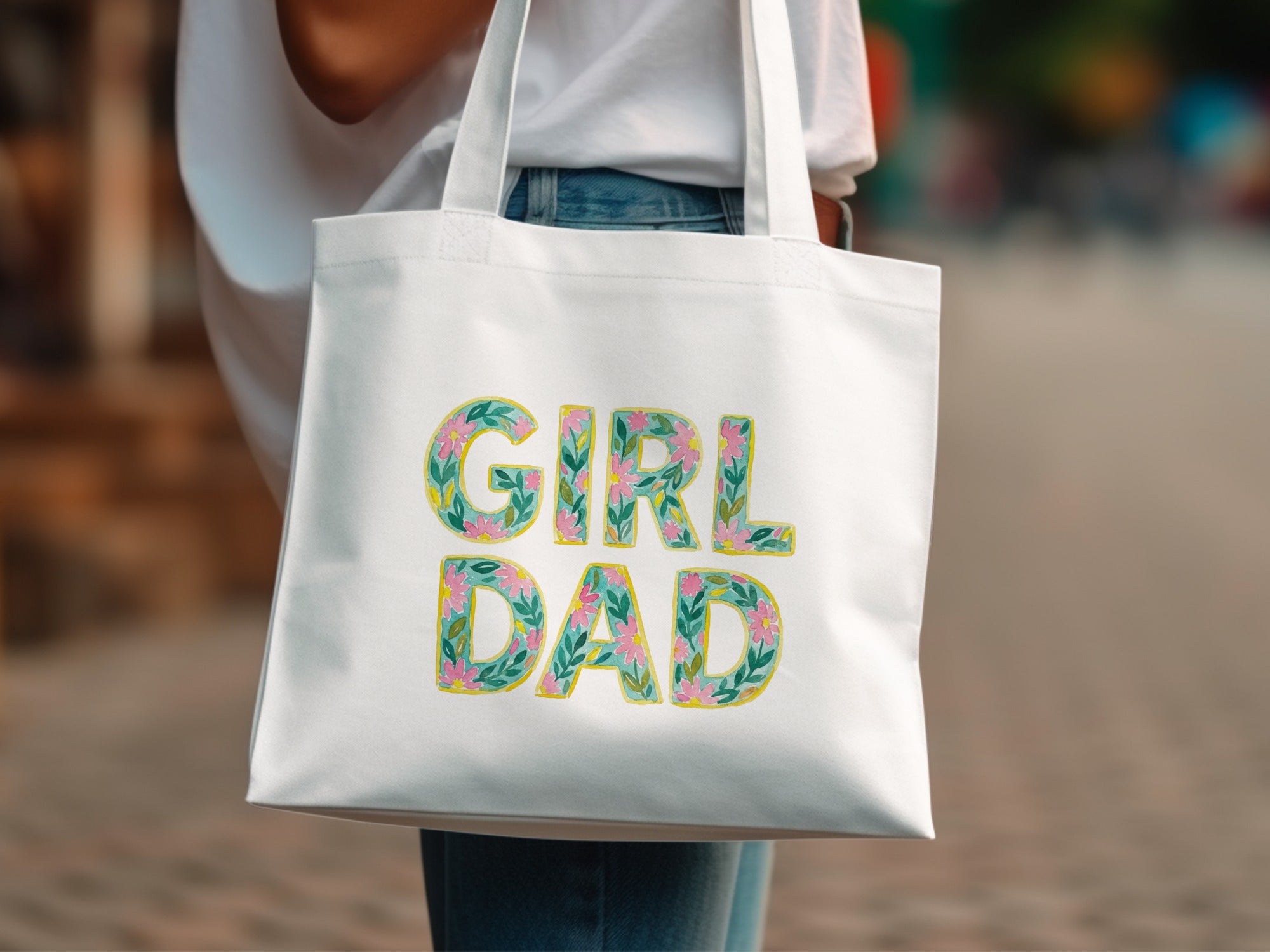 White tote bag with "GIRL DAD" text in floral lettering.