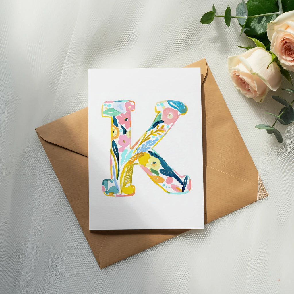 Floral letter K on card with envelope and roses.