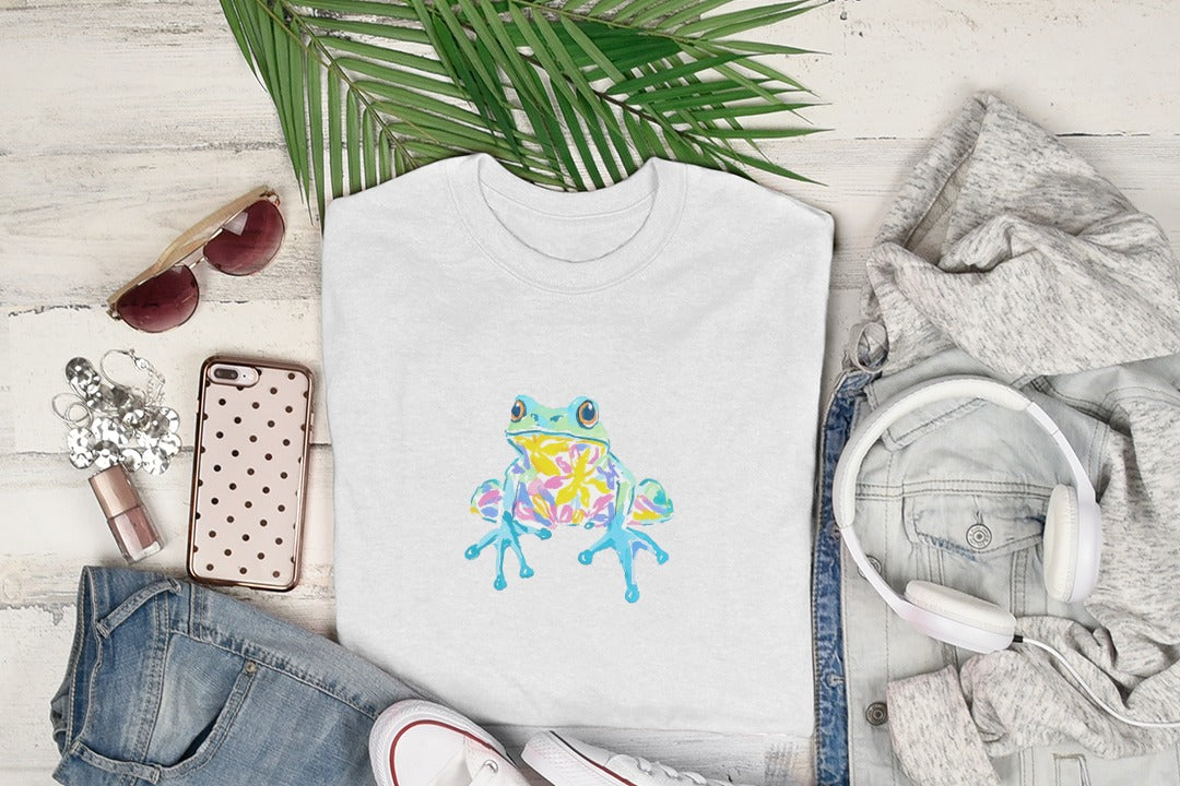 White t-shirt with a colorful cartoon frog illustration.