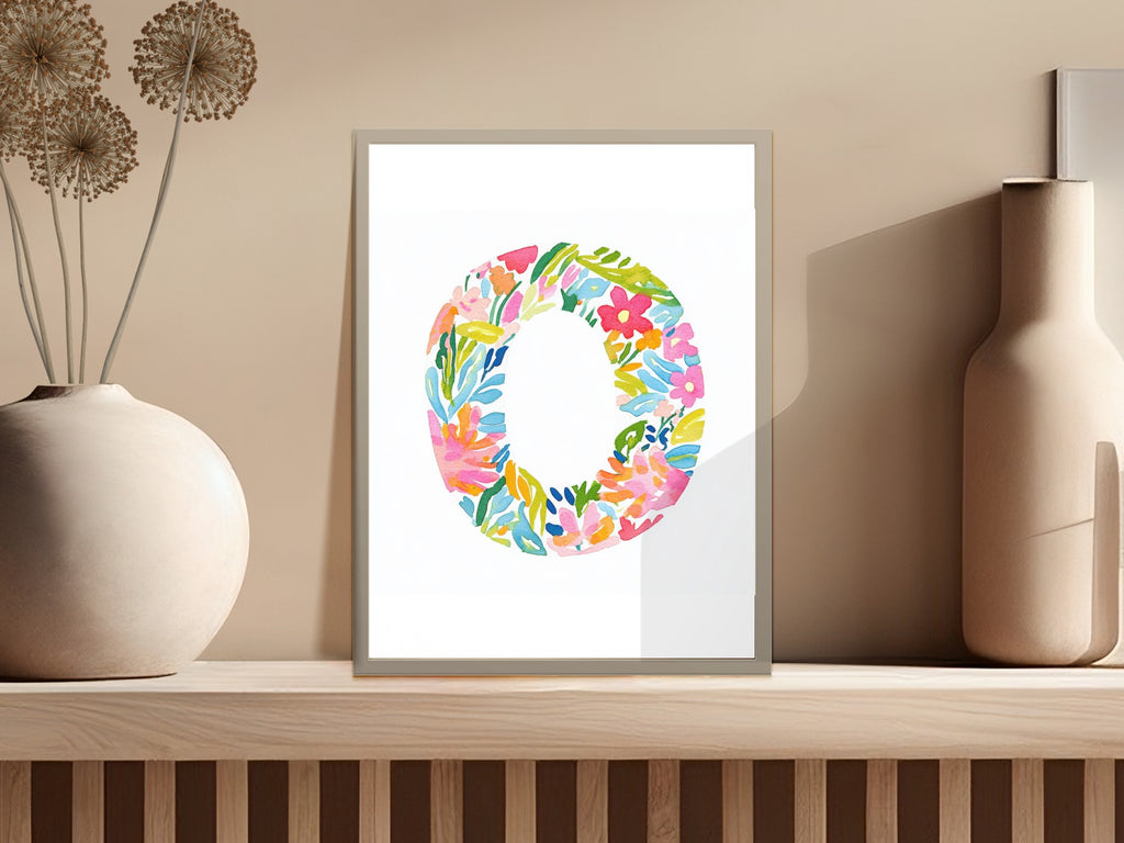 Floral letter O on framed print on shelf.
