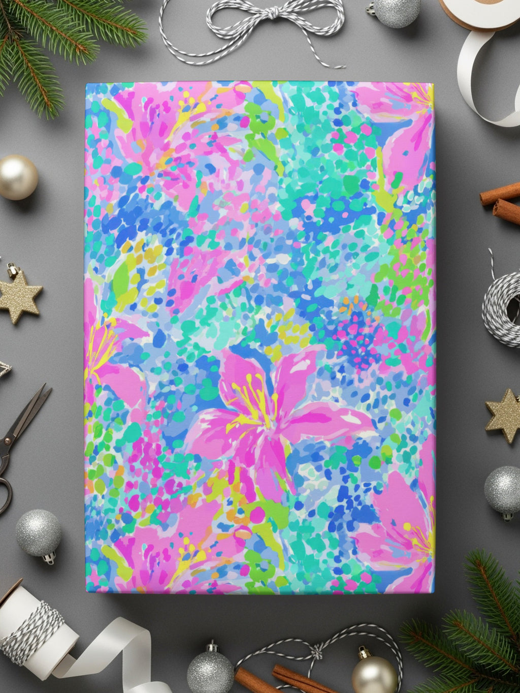 Wrapping paper with colorful floral pattern on gray background, surrounded by ribbon and holiday decorations.
