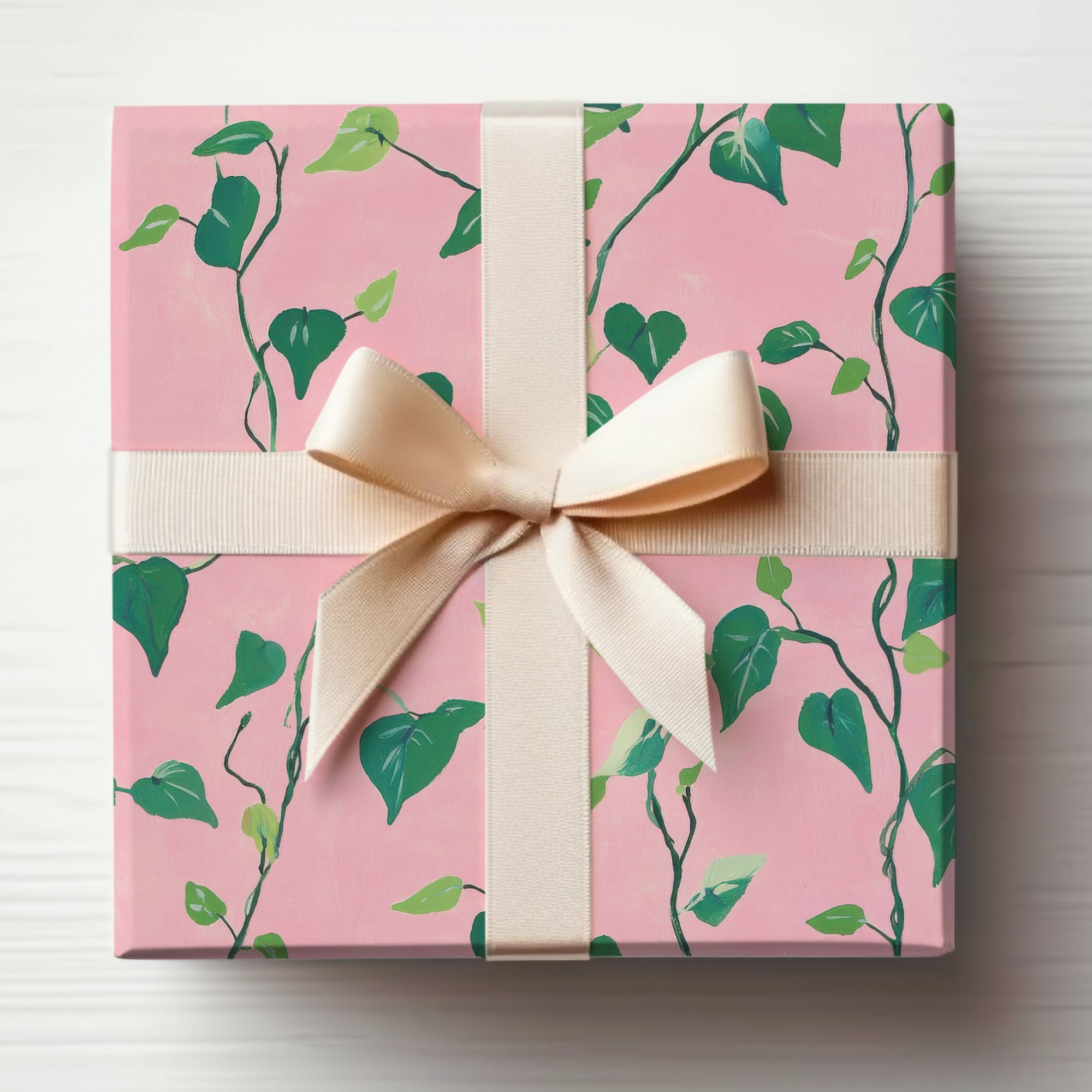 Pink gift box with green ivy pattern and cream ribbon bow.