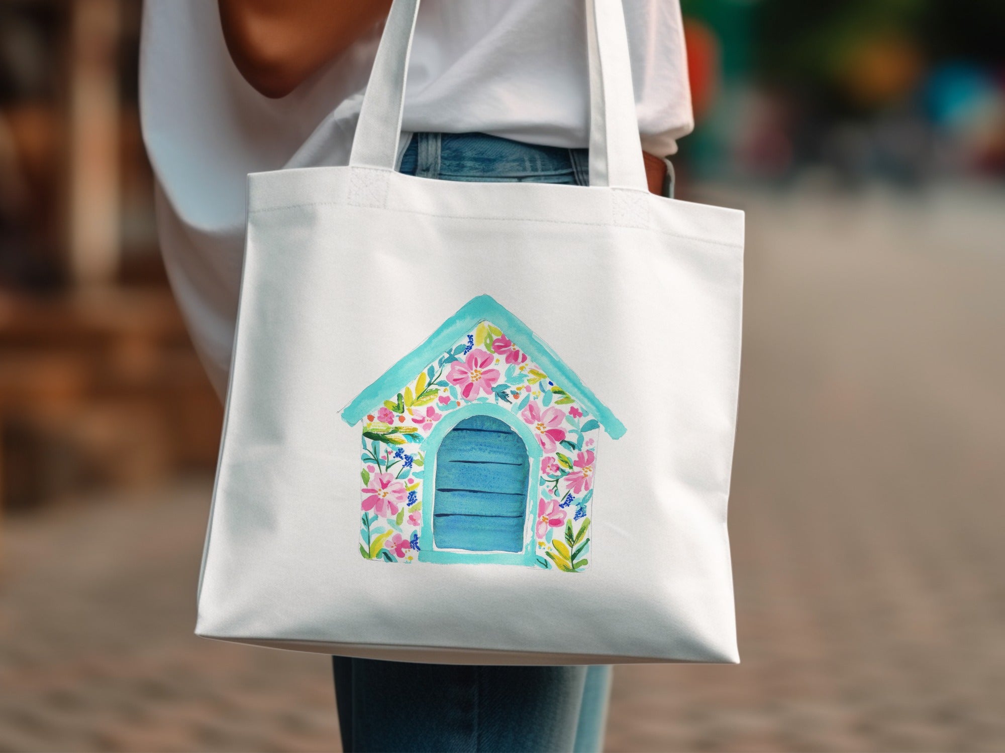 White tote bag with watercolor painting of a blue doghouse with floral accents.
