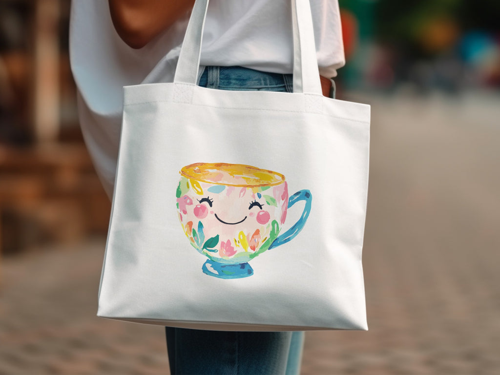 White tote bag featuring a smiling teacup with floral decorations.