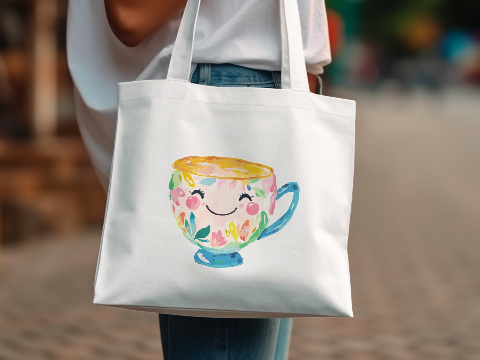 White tote bag featuring a smiling teacup with floral decorations.