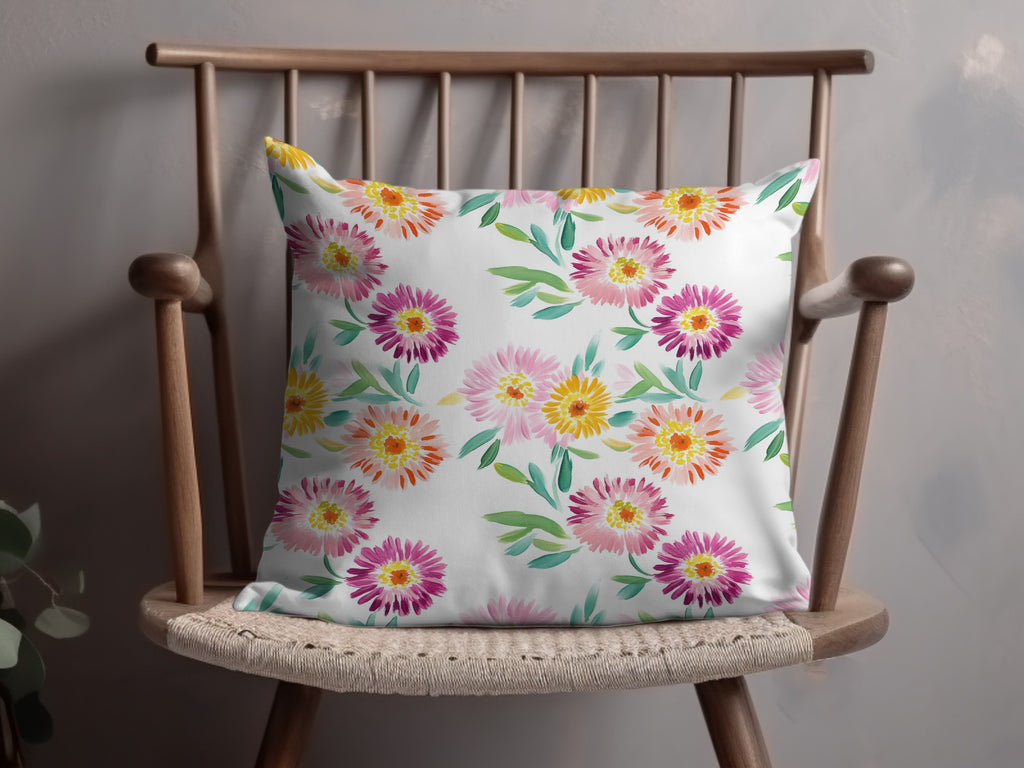 White throw pillow with a floral watercolor pattern of pink and yellow flowers.