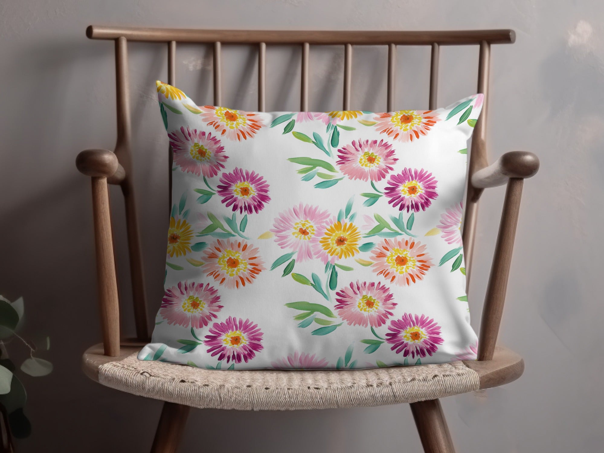 White throw pillow with a floral watercolor pattern of pink and yellow flowers.