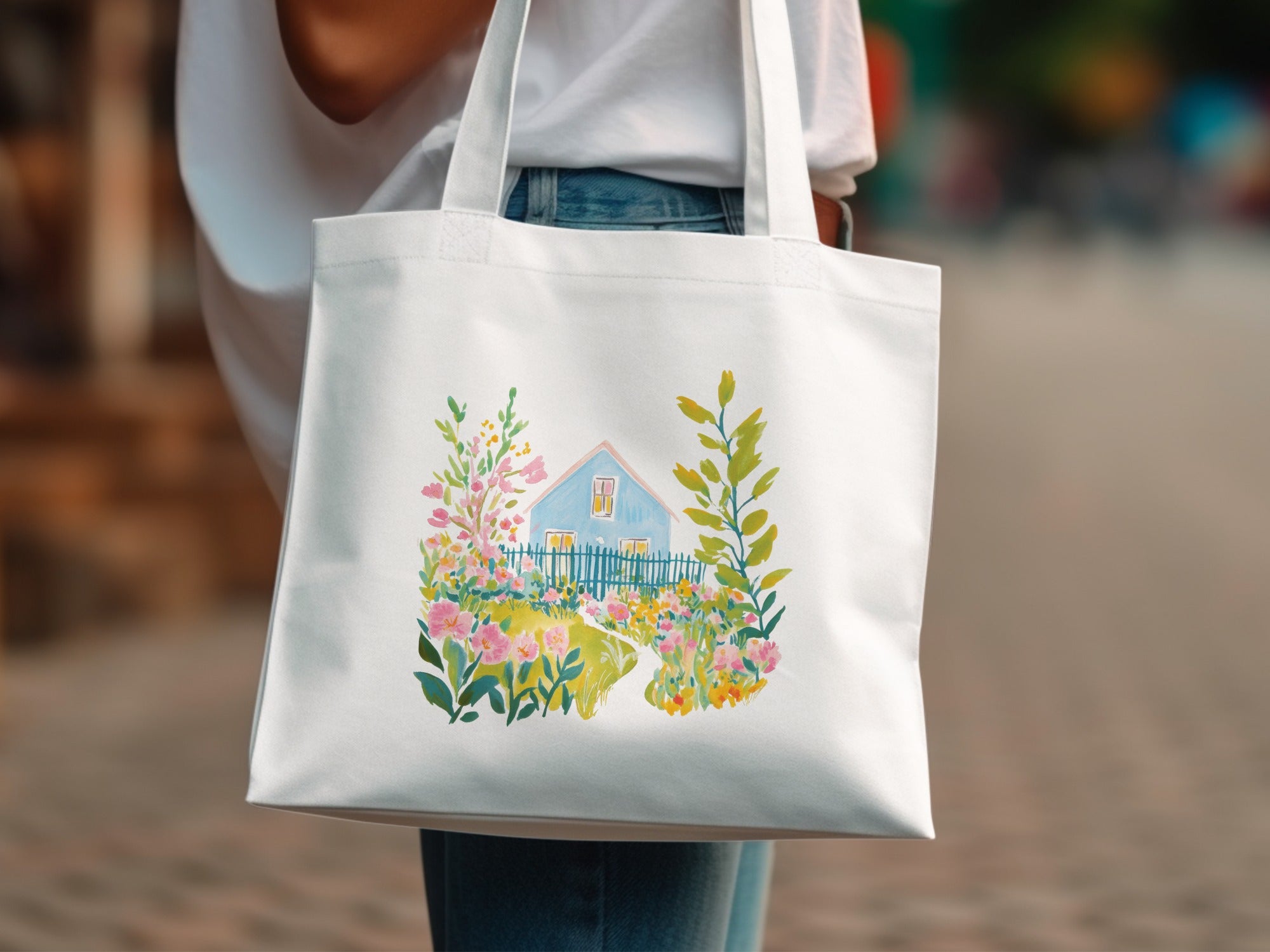White tote bag with a watercolor painting of a house and garden.