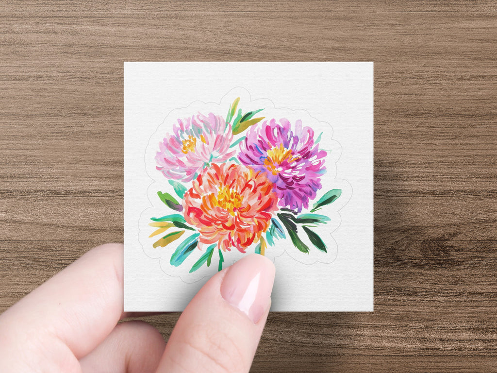 Hand holding a sticker of a colorful floral bouquet.