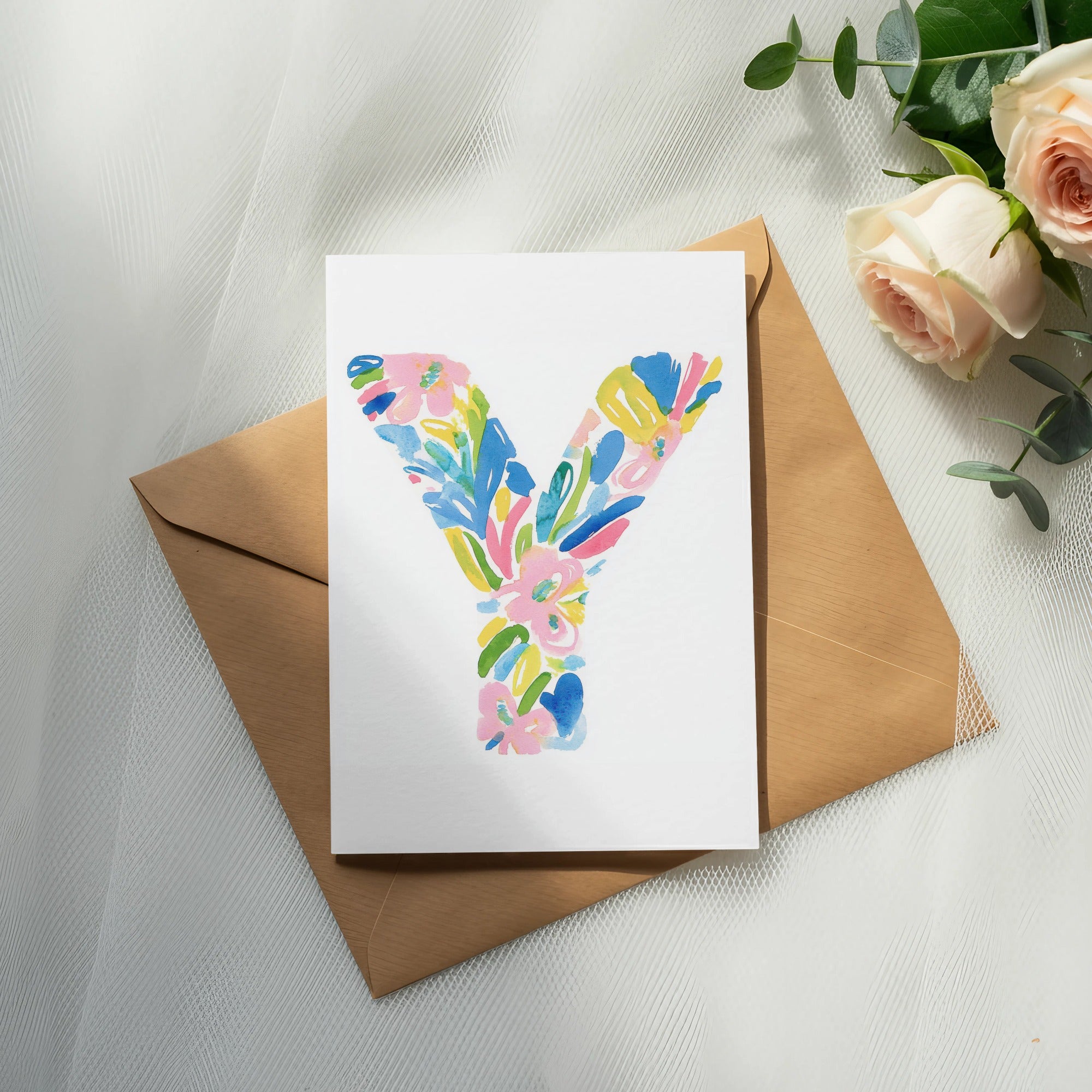 Watercolor letter Y with floral accents on an envelope with roses.