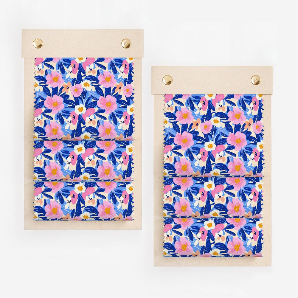 Two fabric swatch books displaying a pink, blue, and yellow floral pattern.