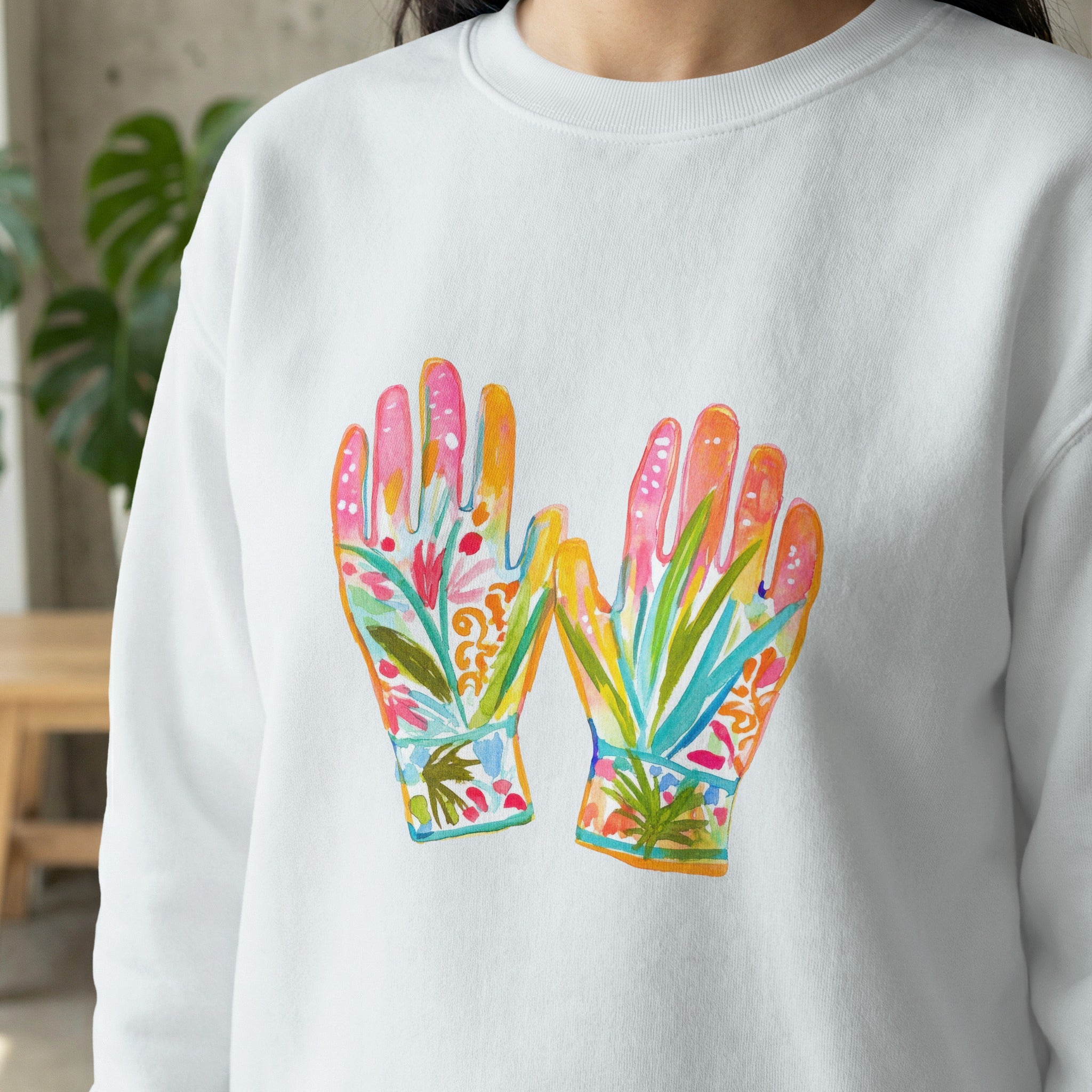 White sweatshirt with watercolor-style floral gloves illustration.