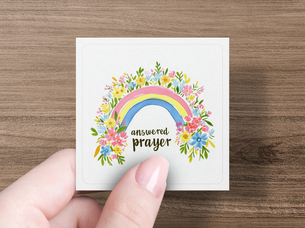 Square card with rainbow and "answered prayer" text surrounded by colorful flowers.