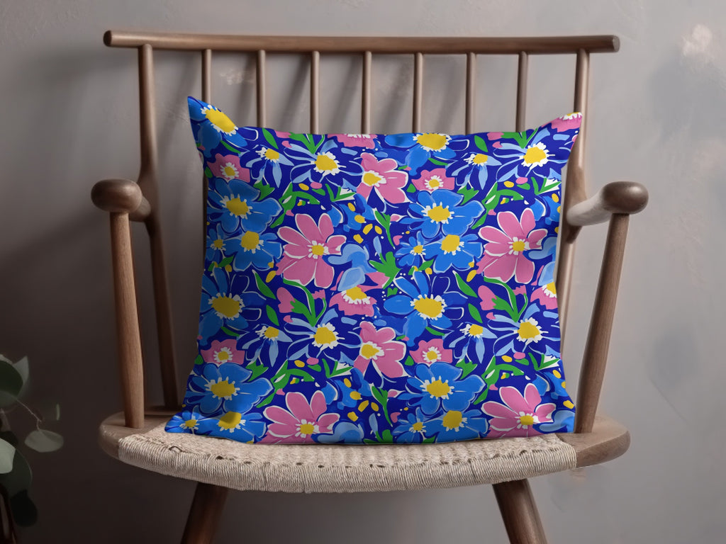 Blue pillow with a repeating pattern of pink and yellow flowers.