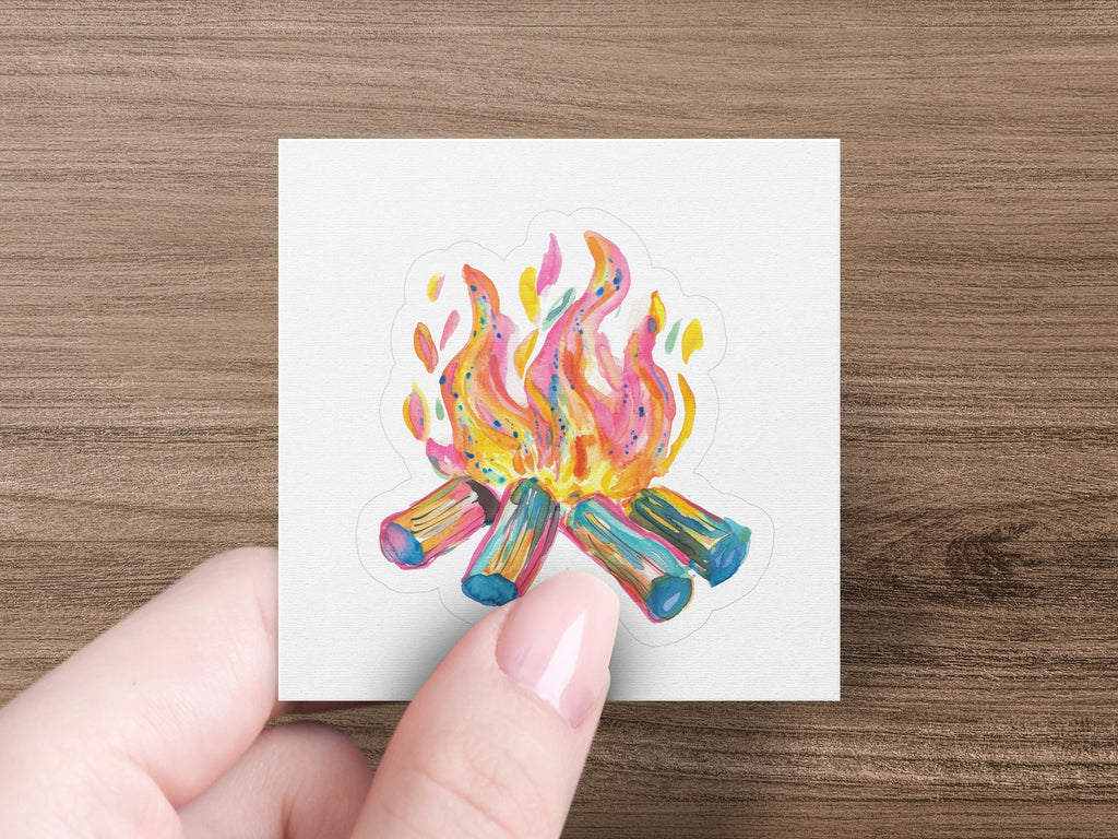 Campfire sticker with colorful flames and logs held by fingers.