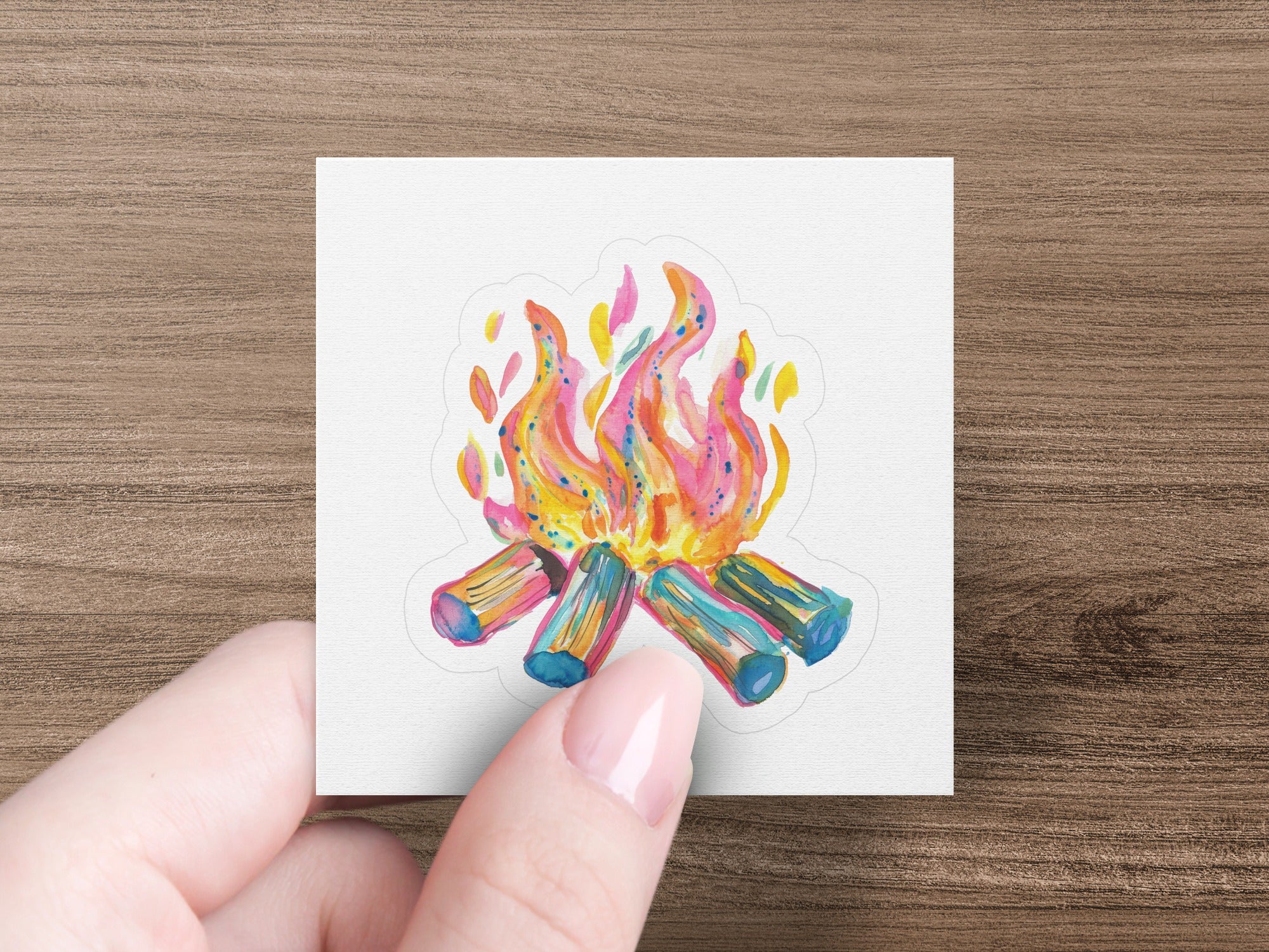 Campfire sticker with colorful flames and logs held by fingers.