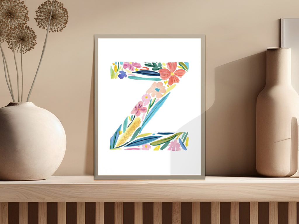 Colorful floral letter Z artwork in a minimalist frame on a shelf.