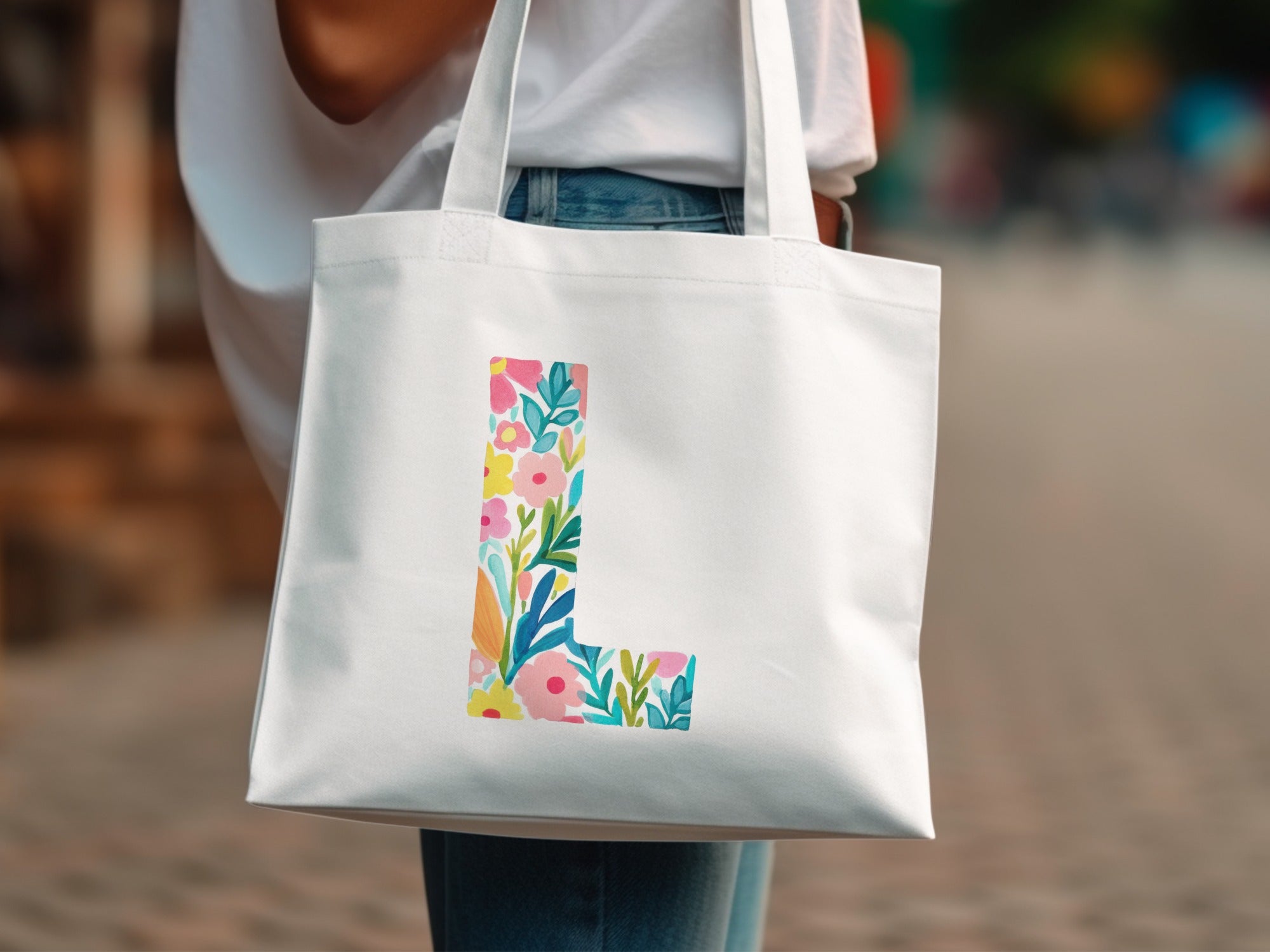 White tote bag with a colorful floral letter "L" design.