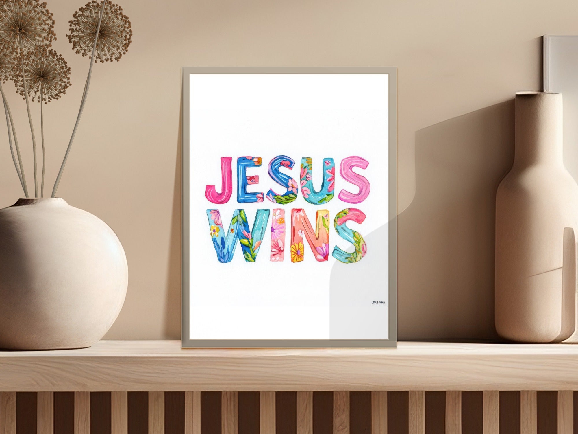 Colorful floral letters spell "Jesus Wins" in a framed print.