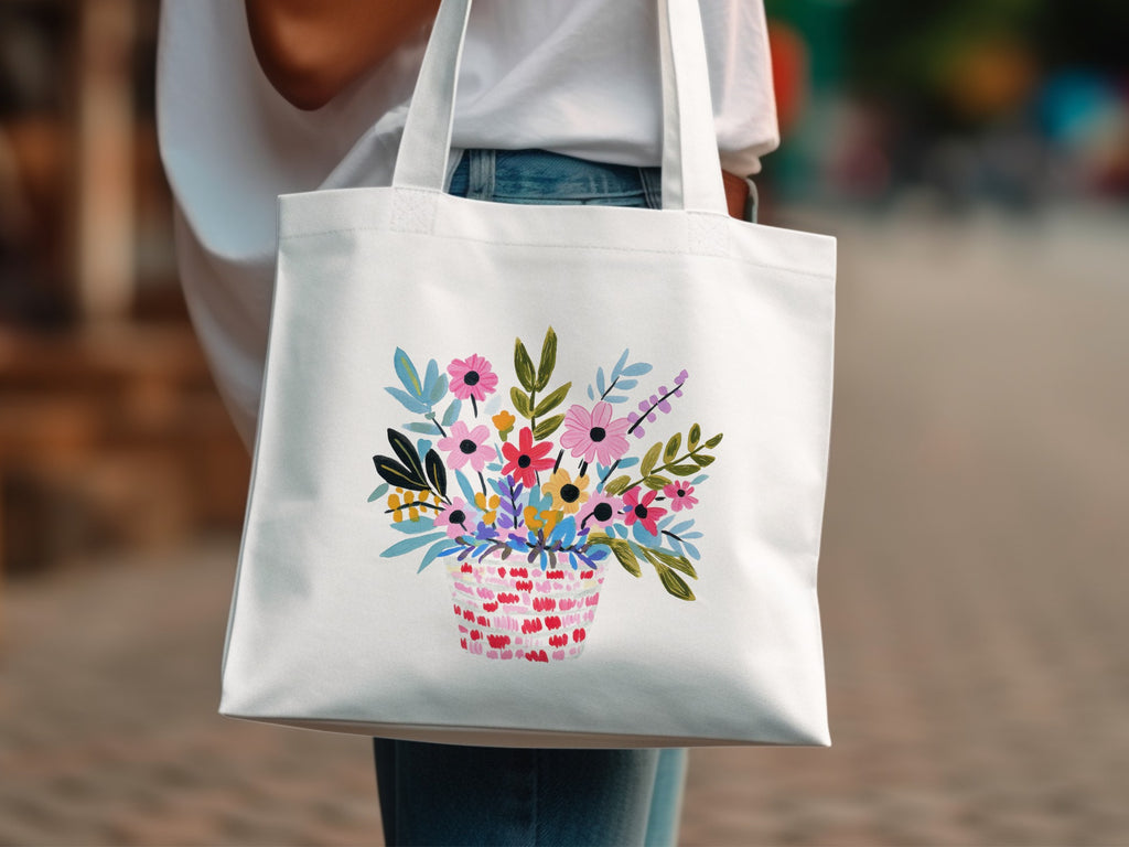 White tote bag with a colorful basket of wildflowers illustration.