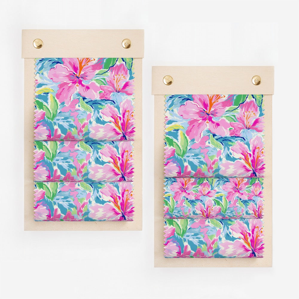 Two swatches of fabric with a bright floral pattern of pink, blue, and green flowers.