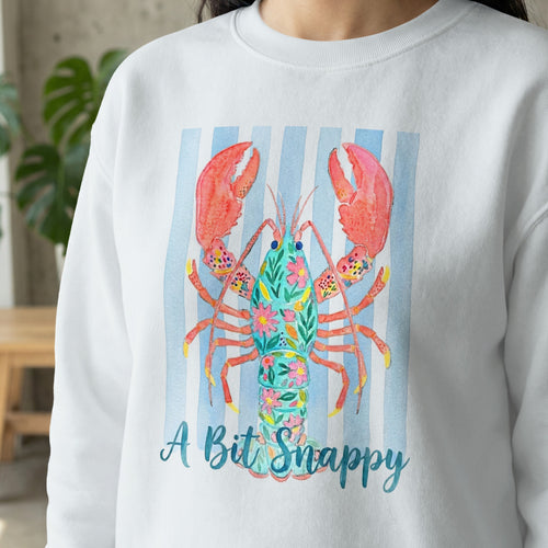 White sweatshirt with blue stripes and colorful lobster graphic, text "A Bit Snappy".