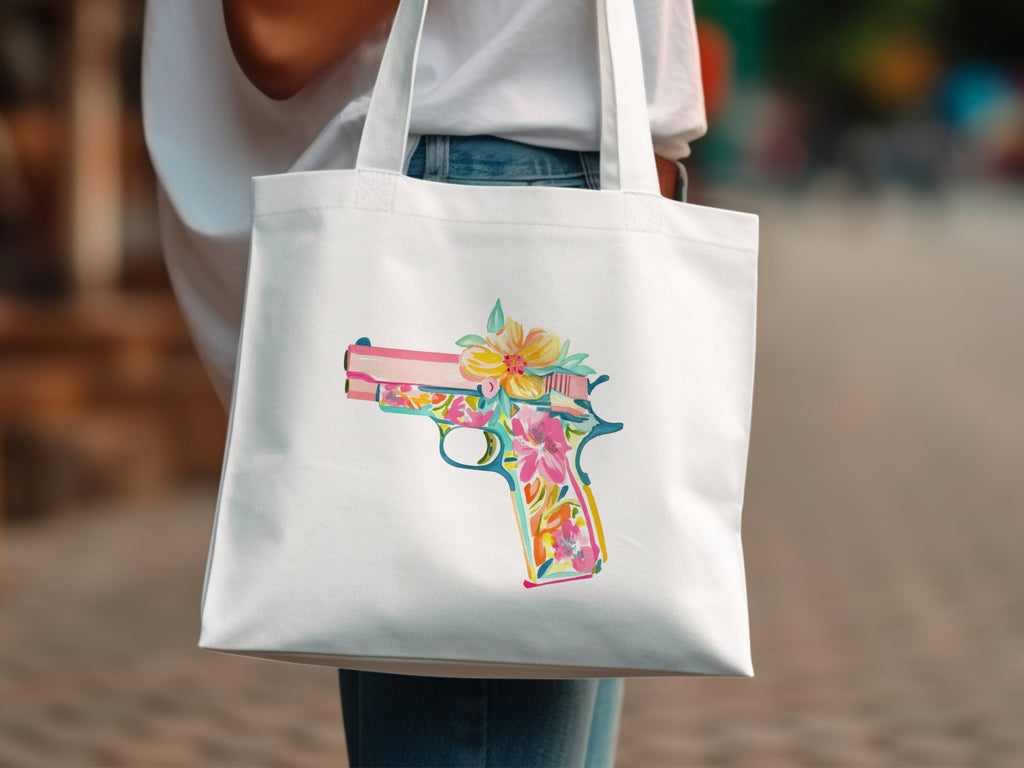 White tote bag with a colorful floral handgun graphic.