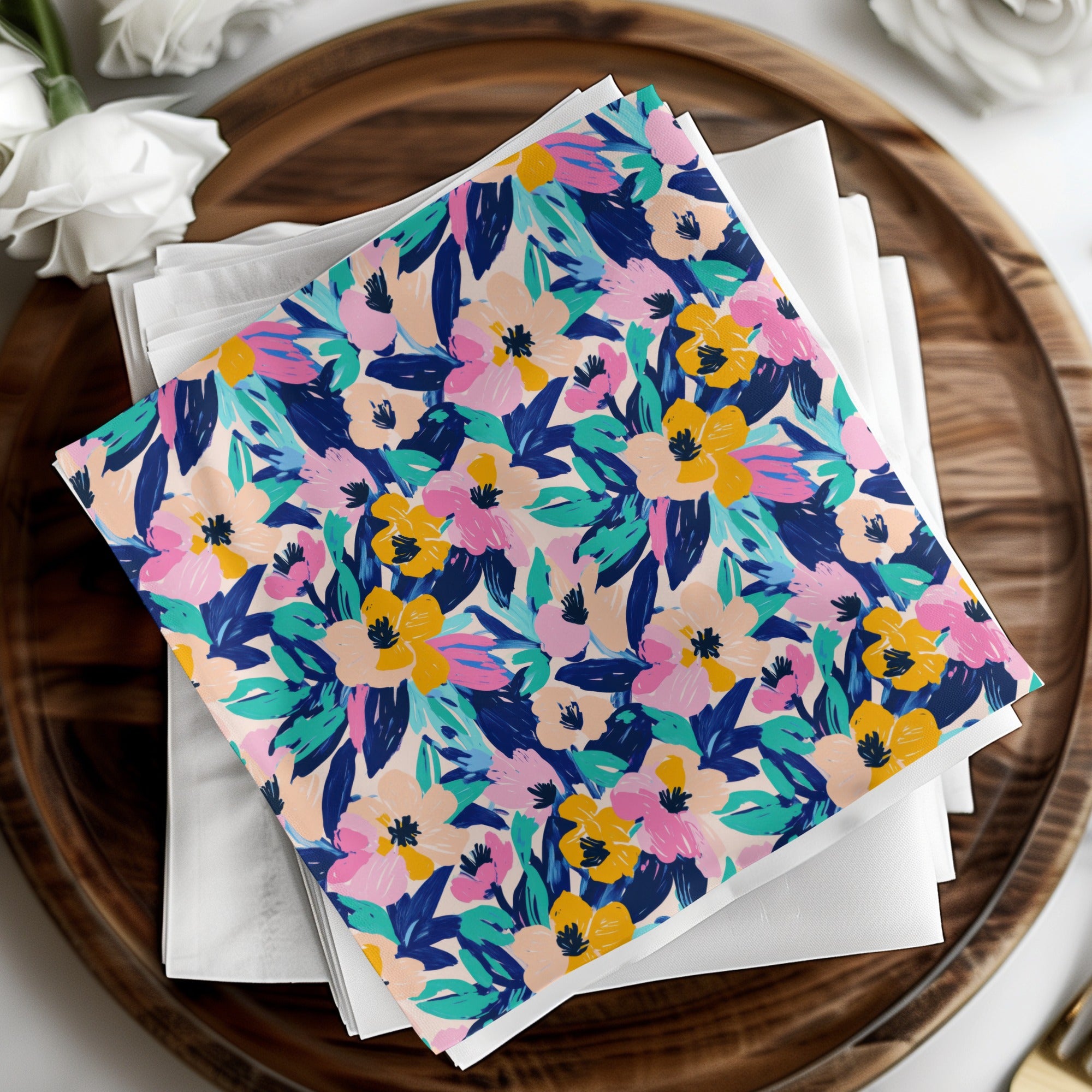 Floral patterned napkins folded on a wooden tray with white flowers.