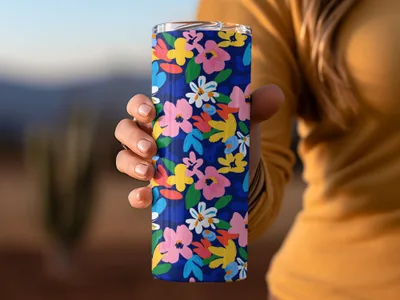 Hand holding a dark blue tumbler with a vibrant floral pattern.
