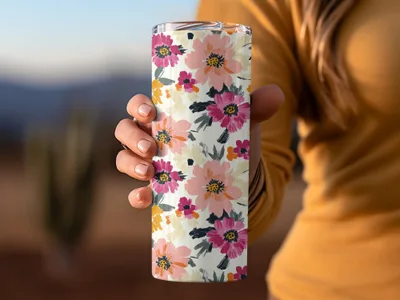 Hand holding a floral tumbler with pink, yellow, and coral flowers.