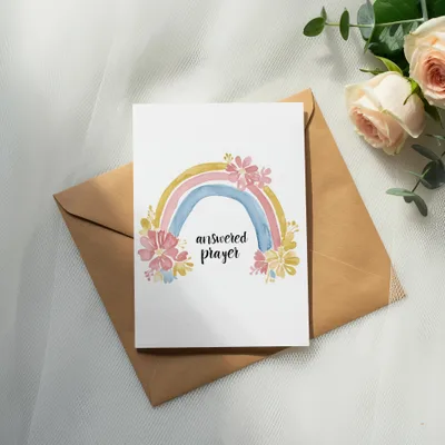 Card with watercolor rainbow and flowers reading "answered prayer" on an envelope.