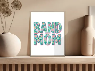 "BAND MOM" text with floral accents in a framed picture on a shelf.