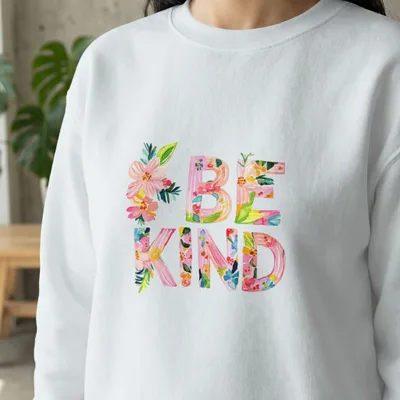 White sweatshirt with colorful floral "BE KIND" lettering.
