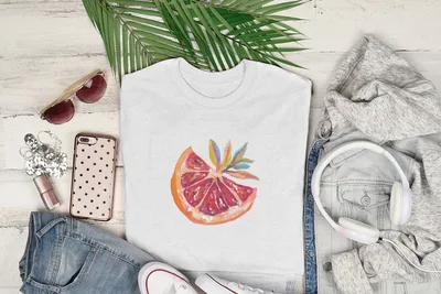 White t-shirt with watercolor orange slice graphic, styled with clothes and headphones.