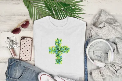 White t-shirt with a green and blue leaf cross design.
