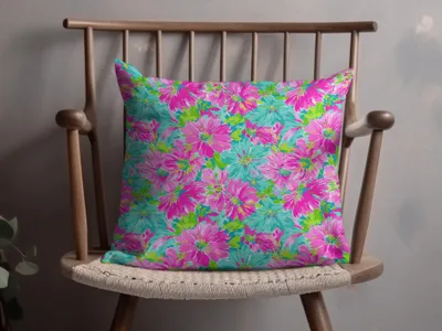 Pillow with a vibrant pink and teal floral pattern on a wooden chair.