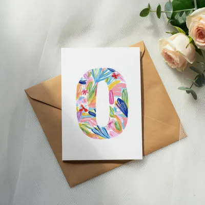 Colorful floral pattern "0" on cardstock, with envelope and roses.