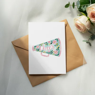 Cheer megaphone with floral design on card atop envelope, with roses.