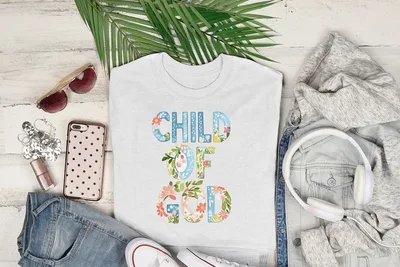 White t-shirt with "Child of God" text surrounded by floral embellishments.