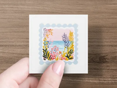 Square sticker with colorful floral and ocean scene held by a hand.
