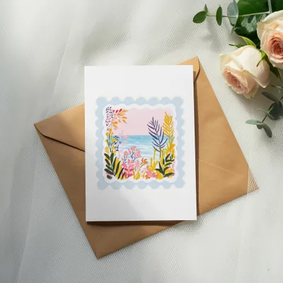 Greeting card with a colorful floral and ocean scene on an envelope.