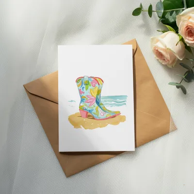 Watercolor cowboy boot with floral pattern on a beach scene, on an envelope.