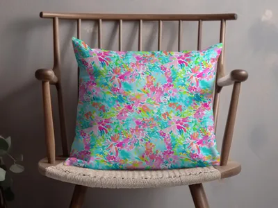 Bright floral patterned throw pillow on a wooden chair.