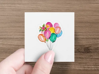 Bunch of colorful balloons and flowers on a white sticker held by a hand.