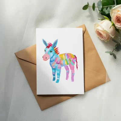 Watercolor painting of a colorful donkey on a card with a brown envelope.